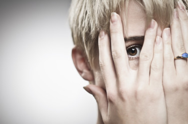 Eye peering through palms covering face