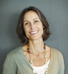 Portrait of stylish middle aged woman smiling against grey background